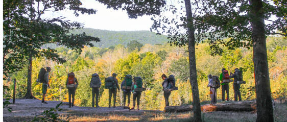 silhouetted backpackers looking down over the Manistee river